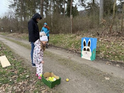 Dívka hází míčky na terč s velikonočním zajíčkem.