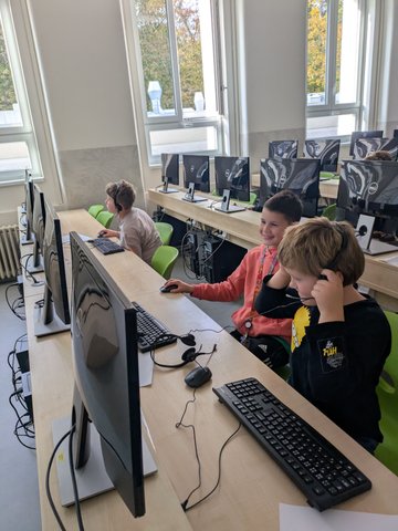 Děti spolupracují u počítačů se sluchátky